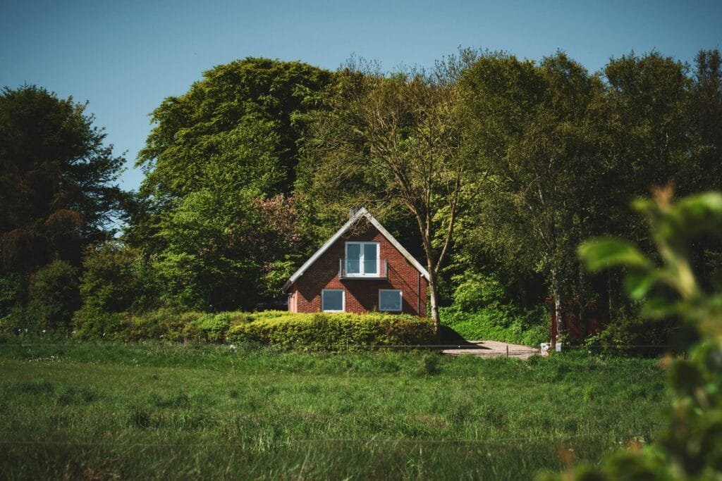 Small red cottage in a green clearing surrounded by trees - ENERGY STAR certification in Barnstable, MA