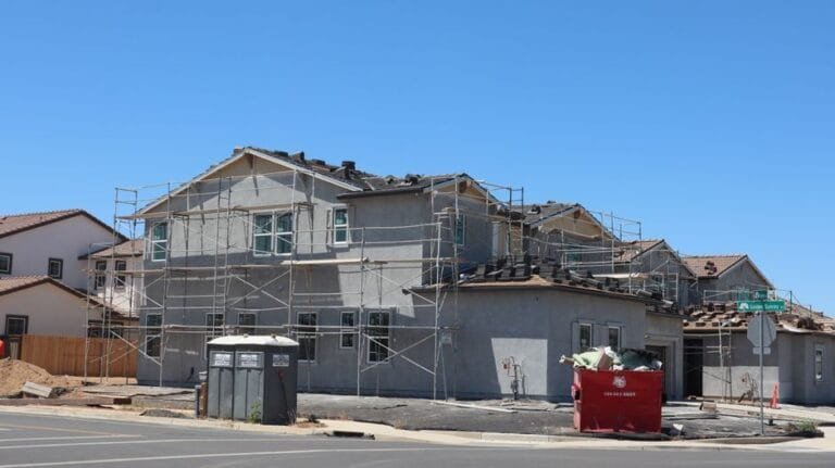Two-story house being re-sided with scaffolding and a dumpster at the curb - HERS rating in Medford, MA