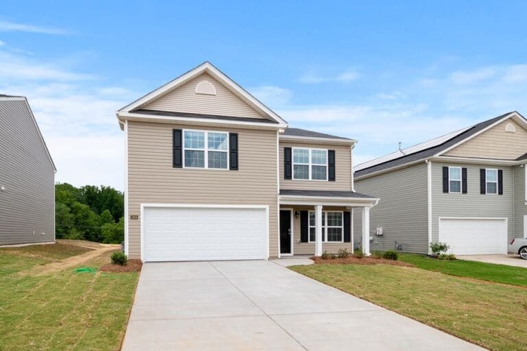 New beige two-story home with a white garage door and a long driveway - HERS rating in Hubbardston, MA