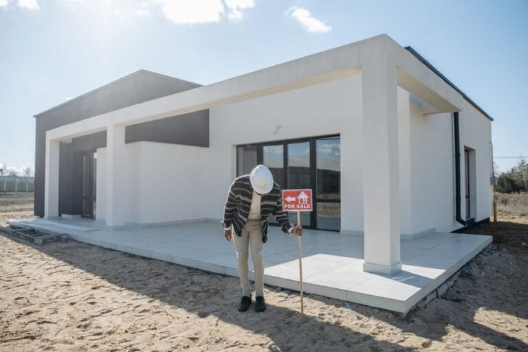 Builder holding plans in front of a new flat-roof white home - HERS rating in New Braintree, MA