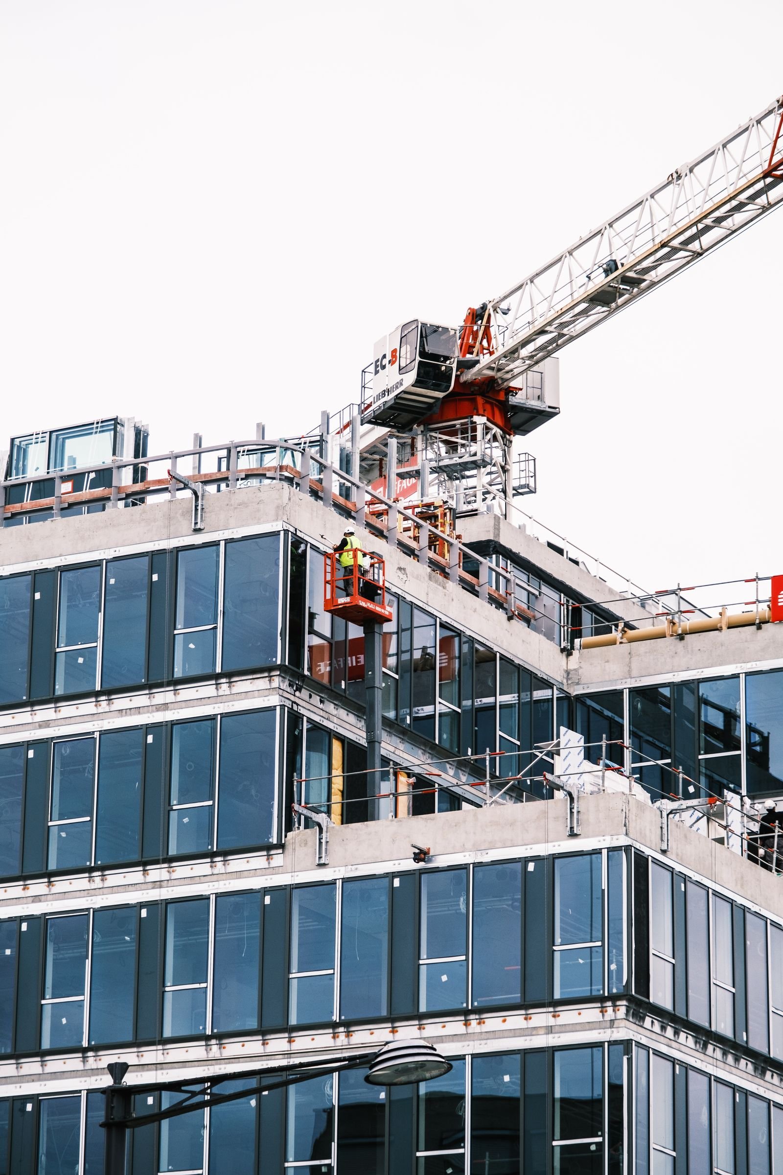 Glass mid-rise building under construction with crane and lifts - Phius Passive House verification in Massachusetts