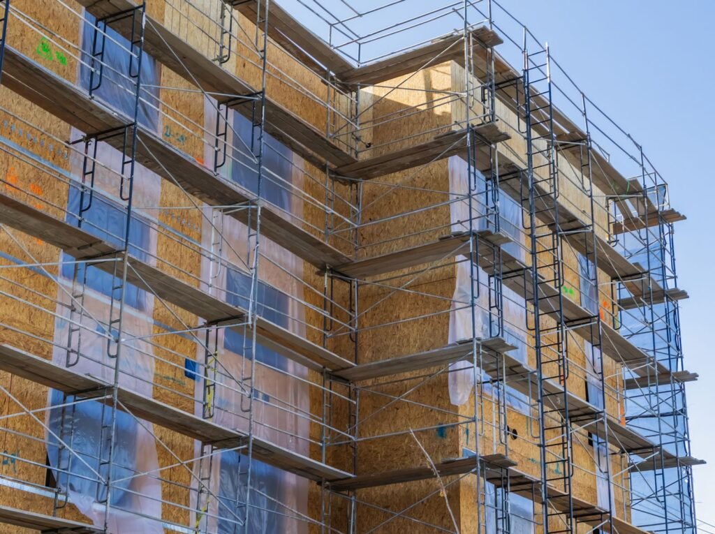 Building corner wrapped in rigid insulation behind steel scaffolding - HERS rating in Cheshire, MA