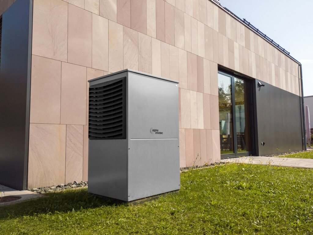 Large heat pump unit on the lawn against a modern terracotta-panel facade - HERS rating in Hopkinton, MA
