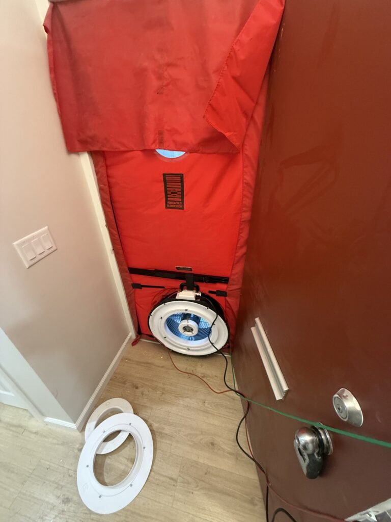 Blower door shroud and fan sealed into a front entry door with flow rings on the floor – HEEC blower door testing for Melrose, MA homes