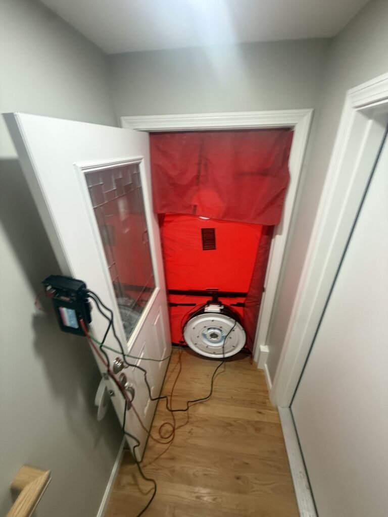 Blower door frame installed in a narrow entry hall with the manometer mounted on the door – HEEC blower door testing for Acushnet, MA homes