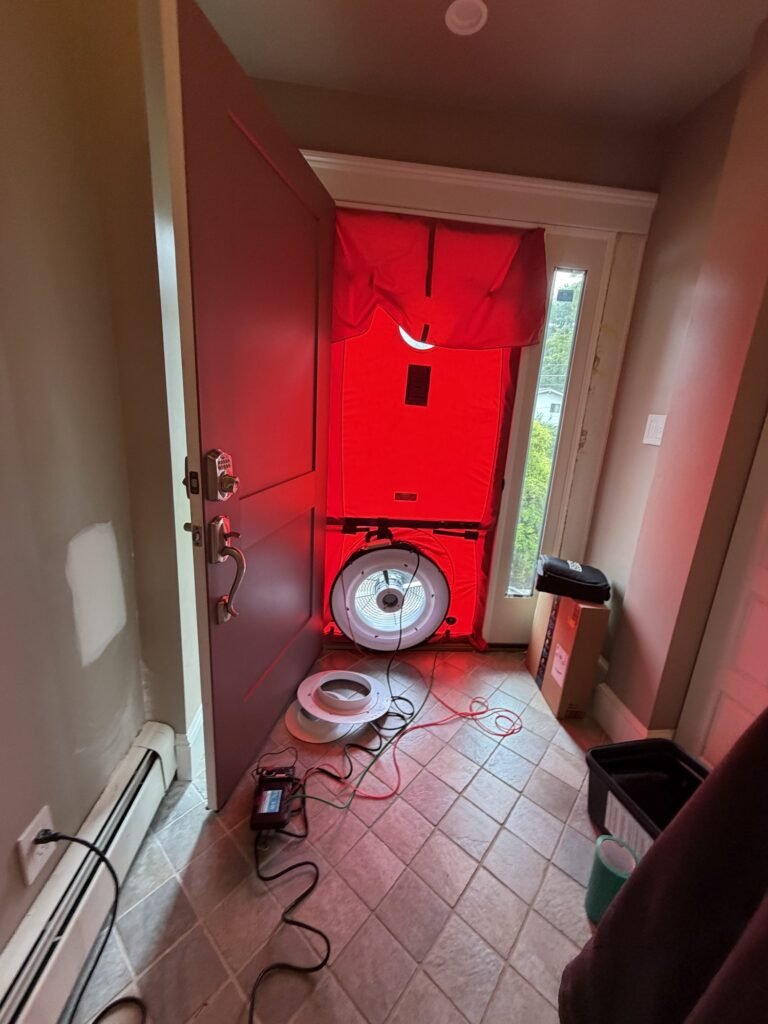 Blower door fan installed in a tiled front entry with a sidelight window – HEEC blower door testing for Hamilton, MA homes