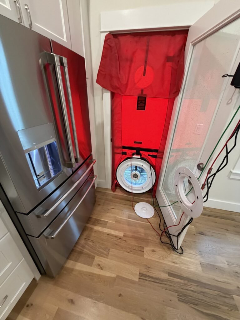Blower door set up in a kitchen side door next to a stainless refrigerator – HEEC blower door testing for Cambridge, MA homes