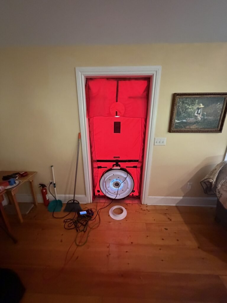 Blower door fan installed in a front door of an older home with wood floors – HEEC blower door testing for Harvard, MA homes