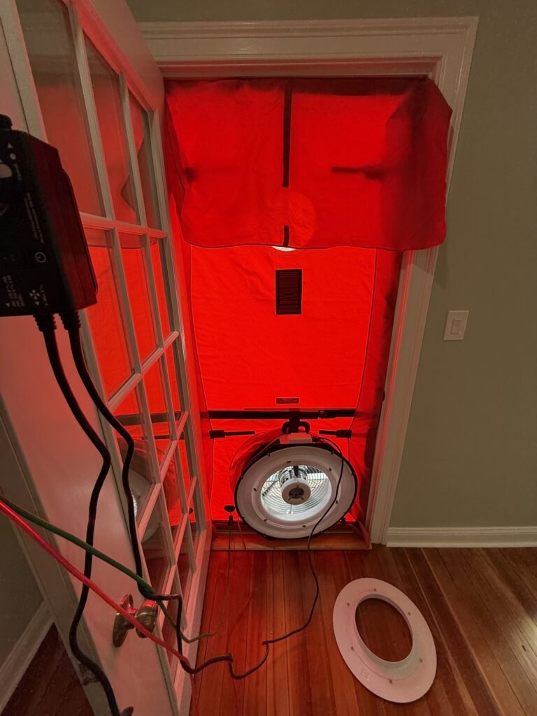 Blower door fan running in a French-style glass door with the gauge on the wall – HEEC blower door testing for Harvard, MA homes