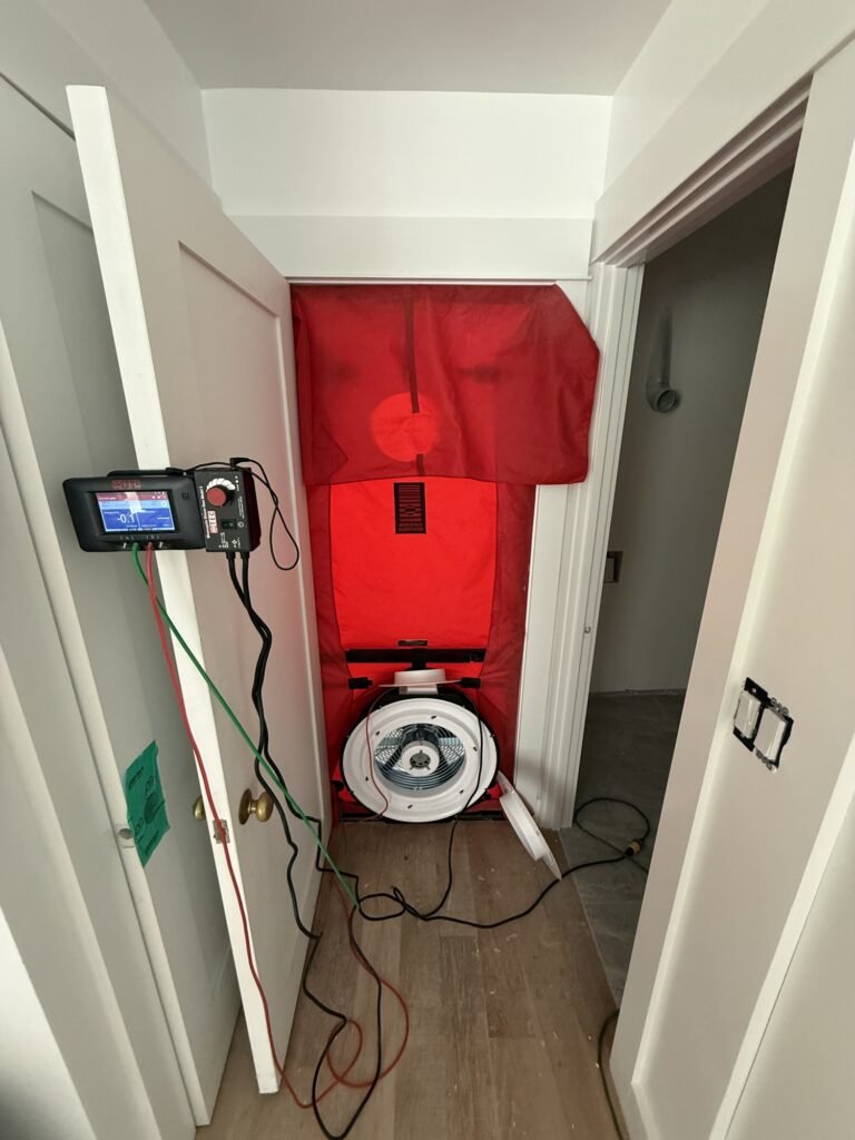 Blower door set up in a hallway door with the manometer mounted on the open door – HEEC blower door testing for Heath, MA homes