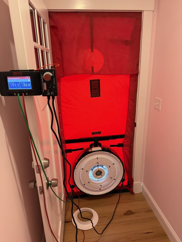 Digital manometer showing house pressure on a door next to the blower door fan - blower door testing in Lawrence, MA