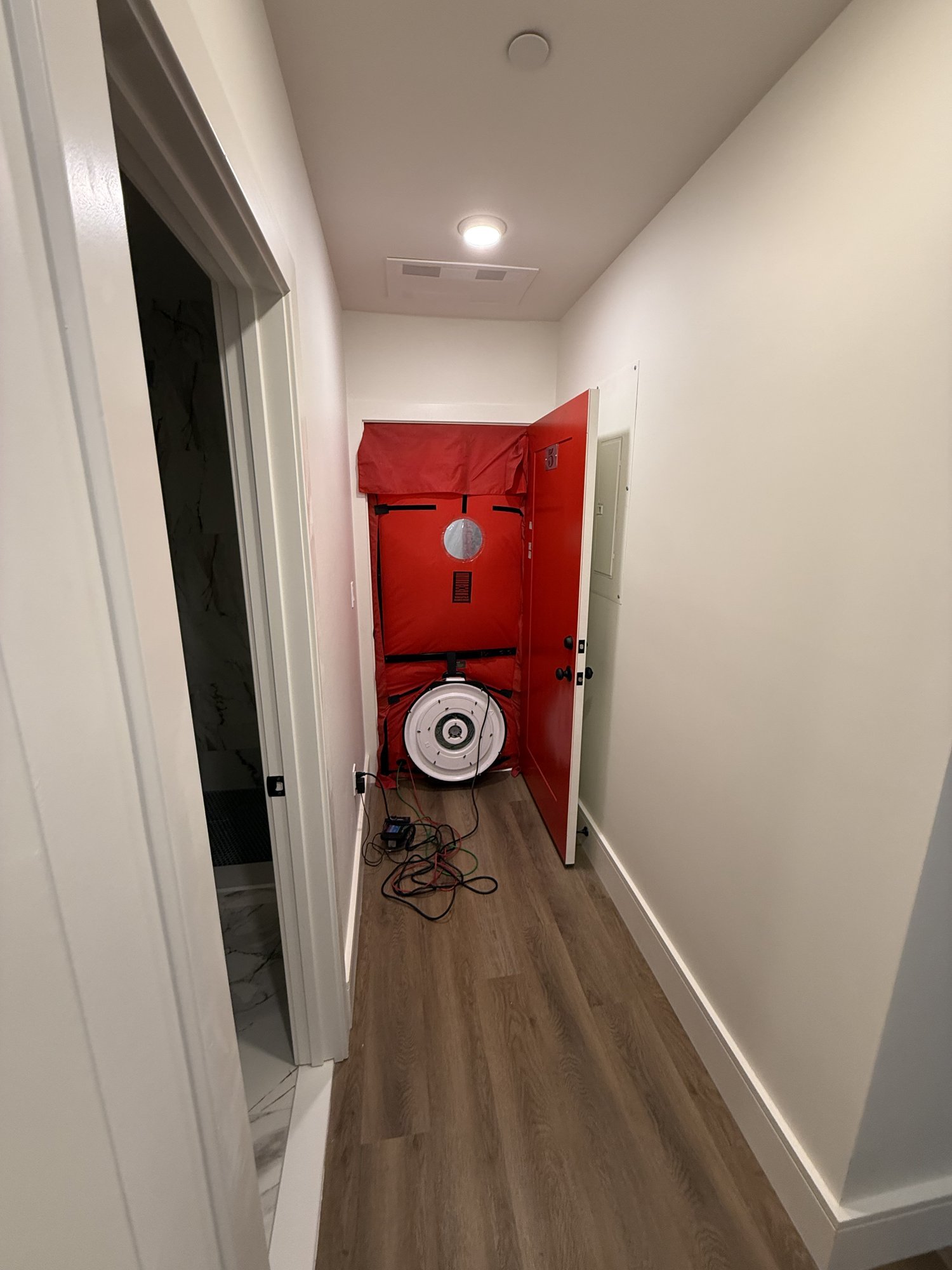 Blower door air leakage test set up at the end of an apartment hallway during a Massachusetts HERS rating