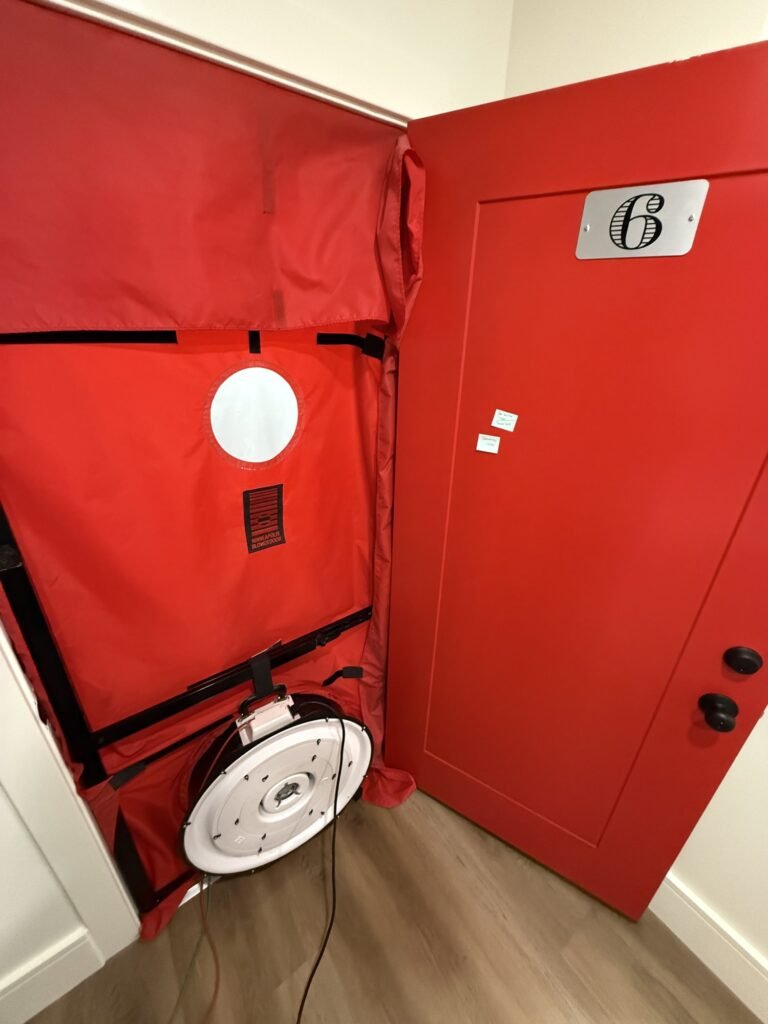 Close view of a blower door sealed into a red apartment unit door – HEEC blower door testing for Medfield, MA homes