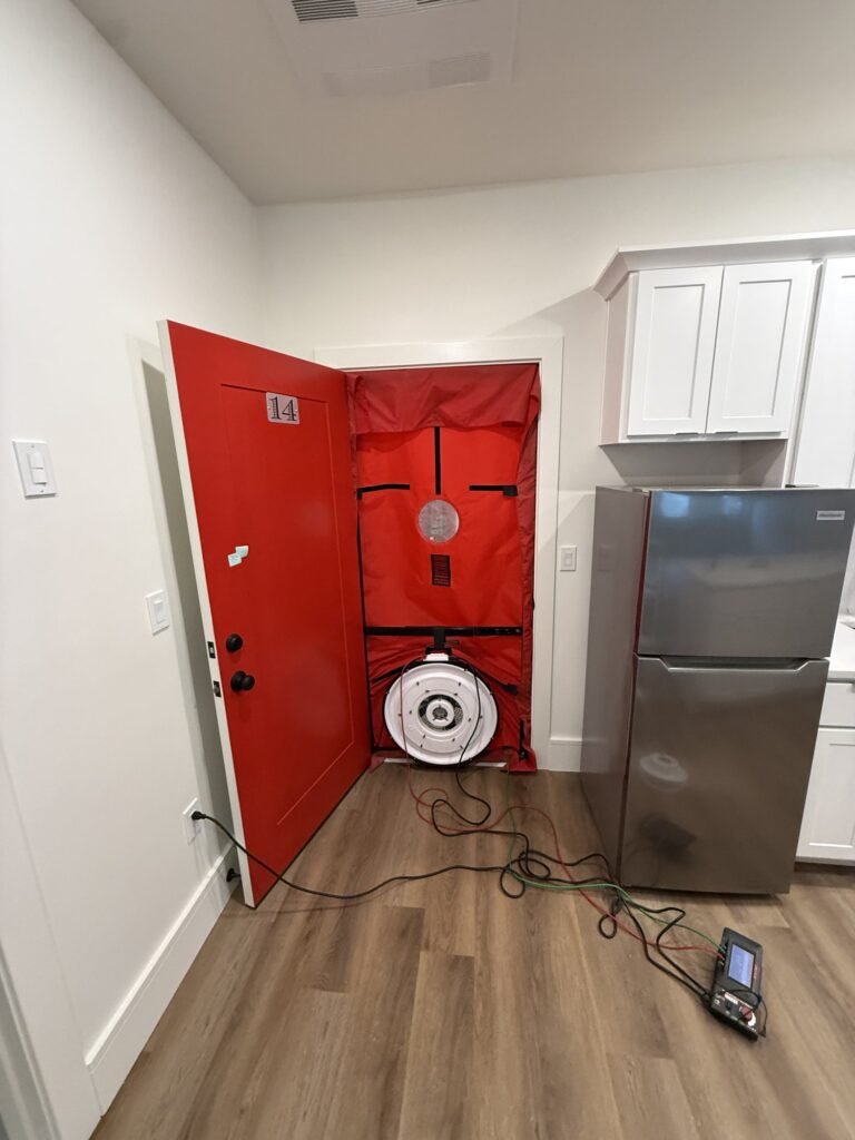 Blower door in a unit entry next to a new kitchen in a multifamily building – HEEC blower door testing for Randolph, MA homes