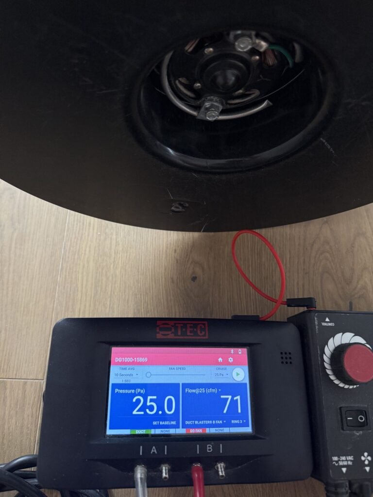 Digital manometer readout sitting below a duct test fan - HERS rating in Harwich, MA