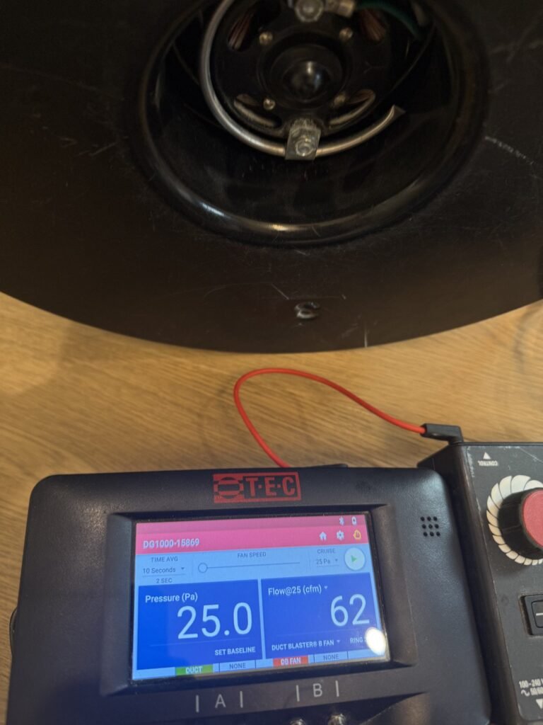 Duct Blaster gauge at 25 Pa test pressure reading 62 CFM25 of total duct leakage on a light oak floor – HEEC duct leakage testing for Acton, MA homes