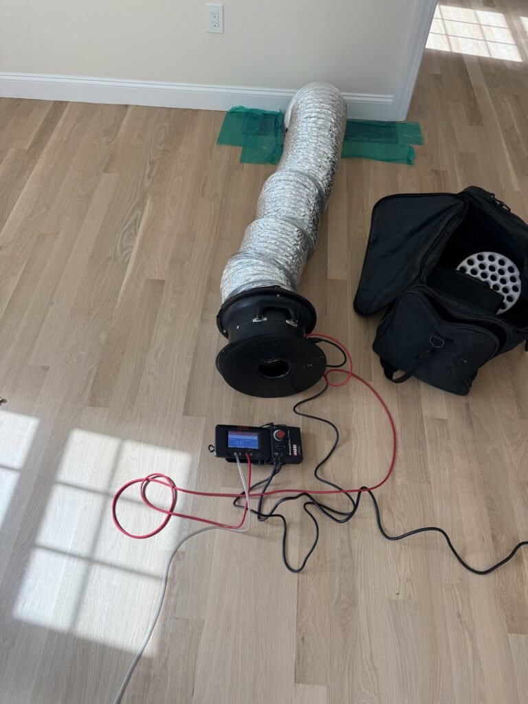 Duct Blaster fan, hose and carry bag set up in a sunny room on a new wide-plank floor – HEEC duct leakage testing for Granby, MA homes