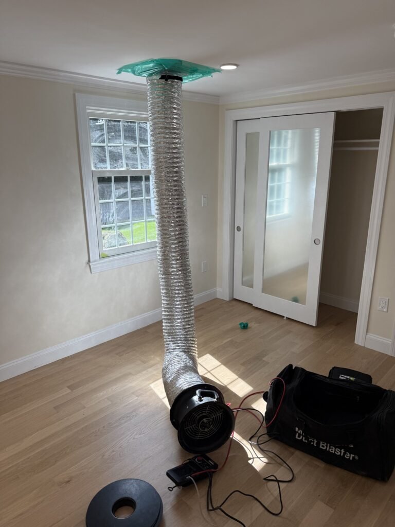 Duct Blaster hose connected to a ceiling return grille in a bedroom with French closet doors – HEEC duct leakage testing for Winthrop, MA homes