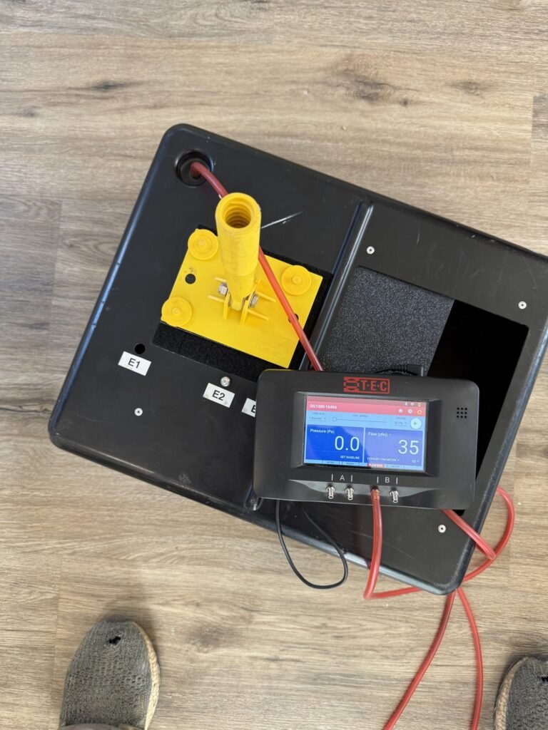 Duct tester with a yellow flow ring resting on a light wood floor - HERS rating in Fall River, MA