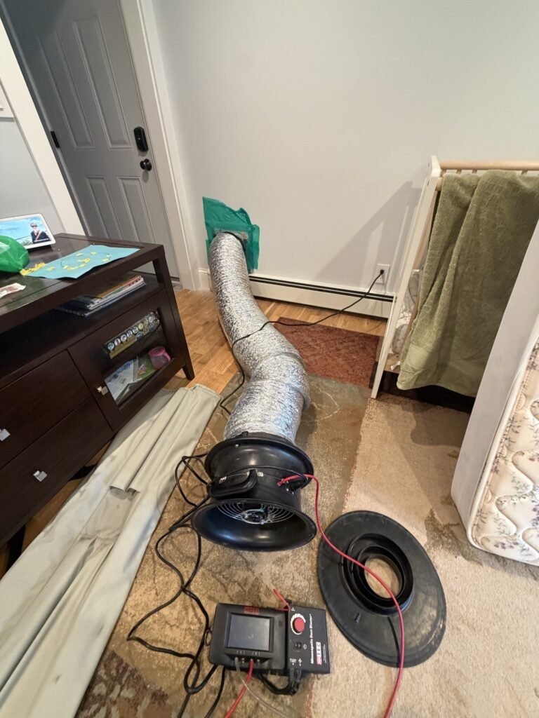 Duct Blaster set up in a bedroom with the hose sealed to a floor return grille – HEEC duct leakage testing for West Brookfield, MA homes