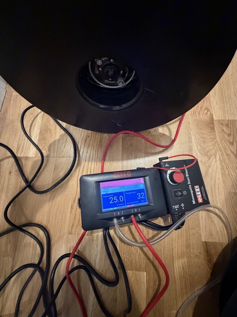 Duct Blaster gauge at 25 Pa test pressure reading 32 CFM25 of total duct leakage with tubing routed to the fan – HEEC duct leakage testing for Dalton, MA homes