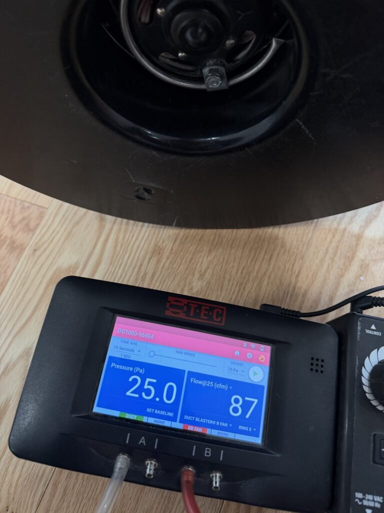 Pressure gauge at the base of a duct testing fan on light wood flooring - HERS rating in Granby, MA