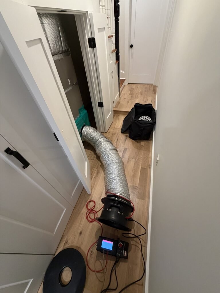 Duct Blaster hose run down a narrow hallway to a sealed return grille – HEEC duct leakage testing for Brewster, MA homes