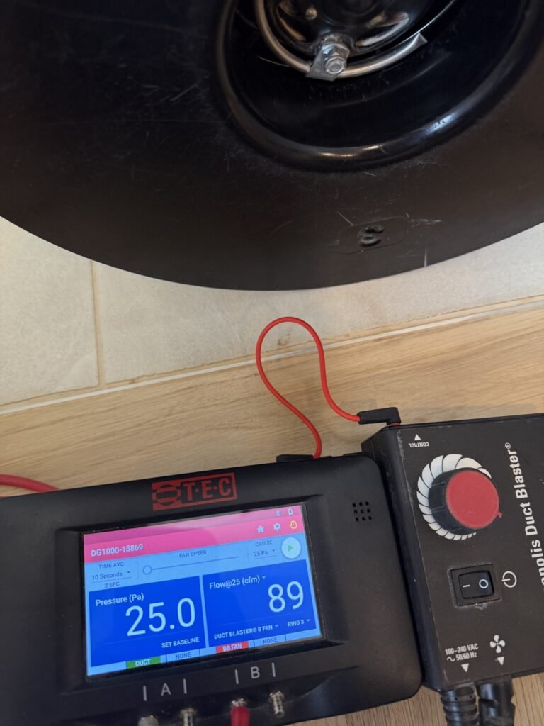 Duct Blaster gauge at 25 Pa test pressure reading 89 CFM25 of total duct leakage on a natural wood floor – HEEC duct leakage testing for Winthrop, MA homes