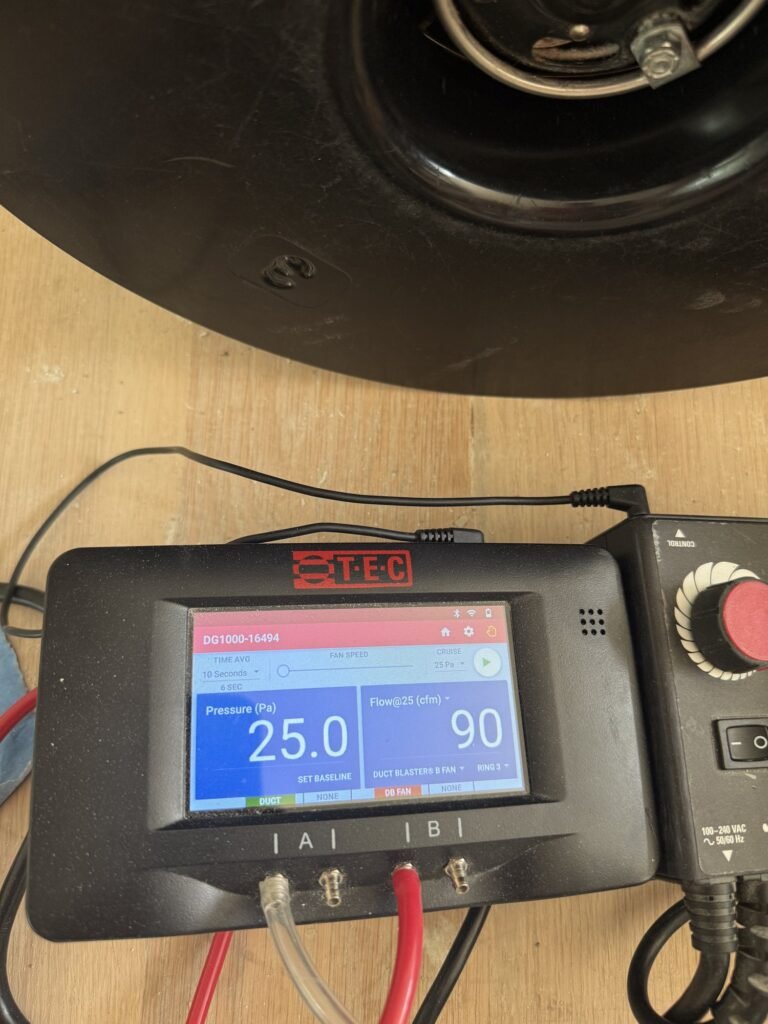 Duct Blaster gauge at 25 Pa test pressure reading 90 CFM25 of total duct leakage on a light wood floor – HEEC duct leakage testing for Charlton, MA homes