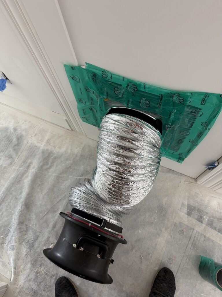 Close-up of the Duct Blaster flex duct sealed to a wall return grille with green tape – HEEC duct leakage testing for Pepperell, MA homes