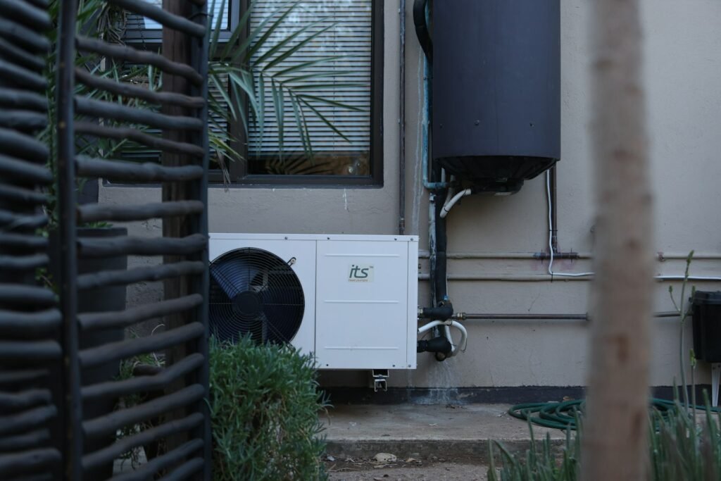 Wall-mounted heat pump condenser behind a dark slatted privacy screen - HERS rating in Lee, MA