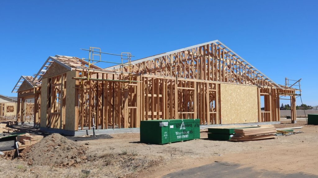 Single-story home in the framing stage with a green dumpster out front - HERS rating in Harvard, MA