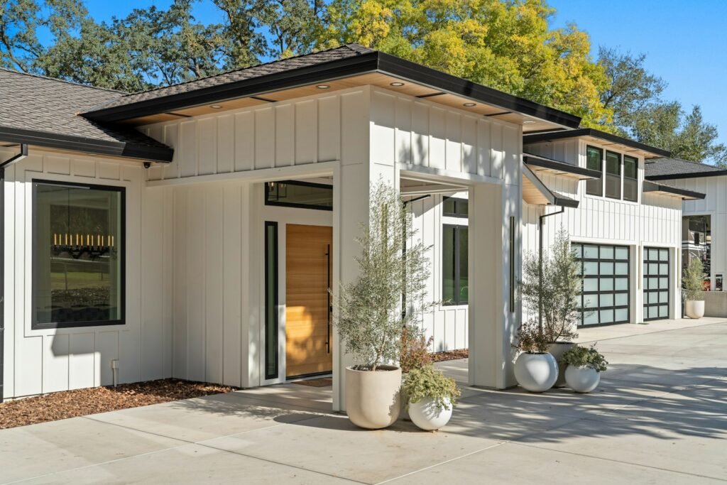 Board-and-batten modern home entry with potted plants and a garage - HERS rating in Holland, MA