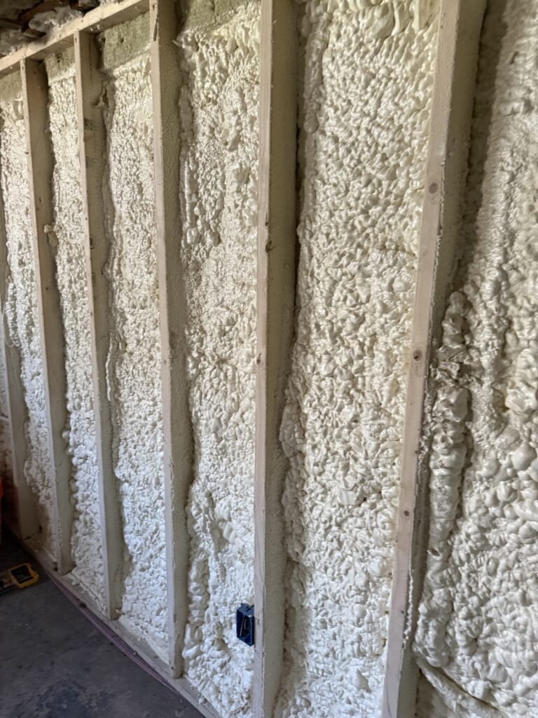 Close-up of spray foam expanded tight between wall studs around an electrical box - spray foam insulation in Becket, MA