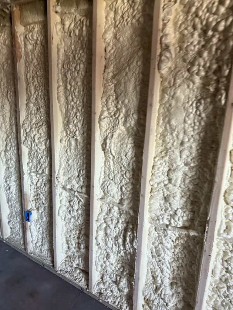 Close view of irregular spray foam filling deep stud bays - HERS rating in Eastham, MA