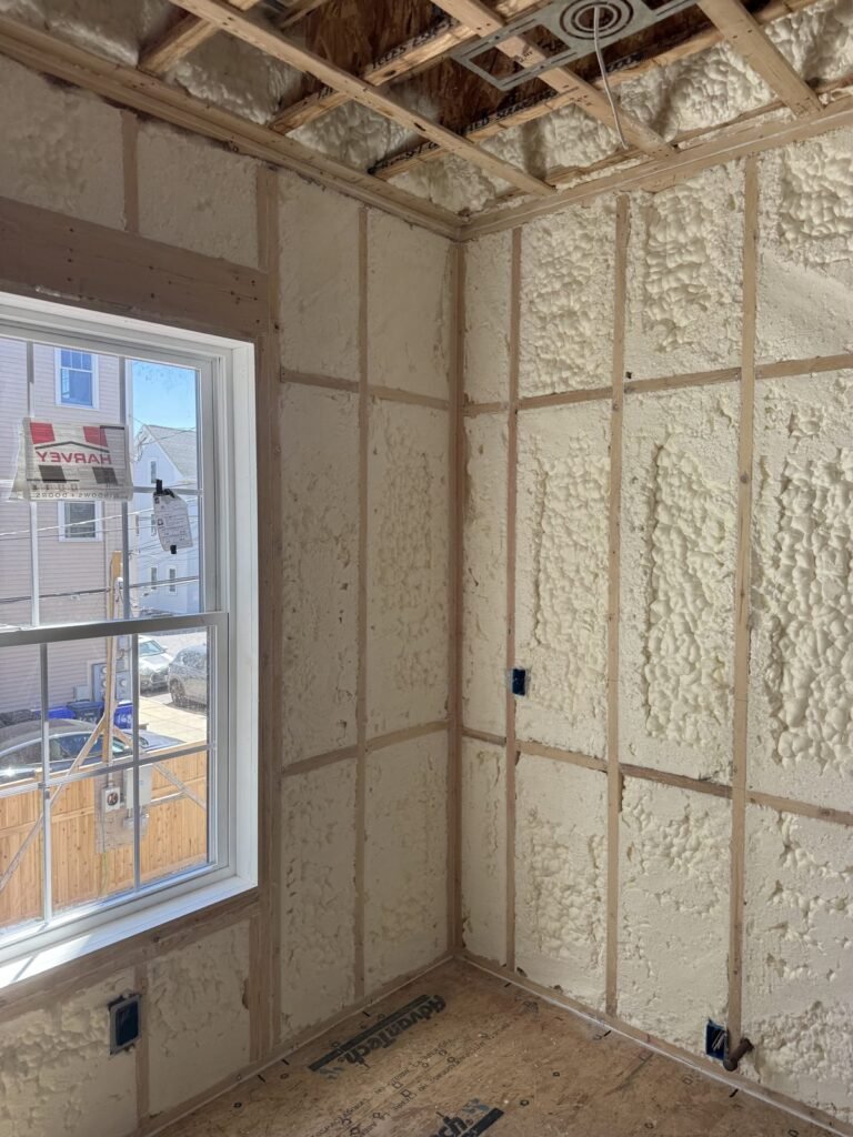 Spray-foamed walls around a double-hung window in a new bedroom - HERS rating in Somerville, MA