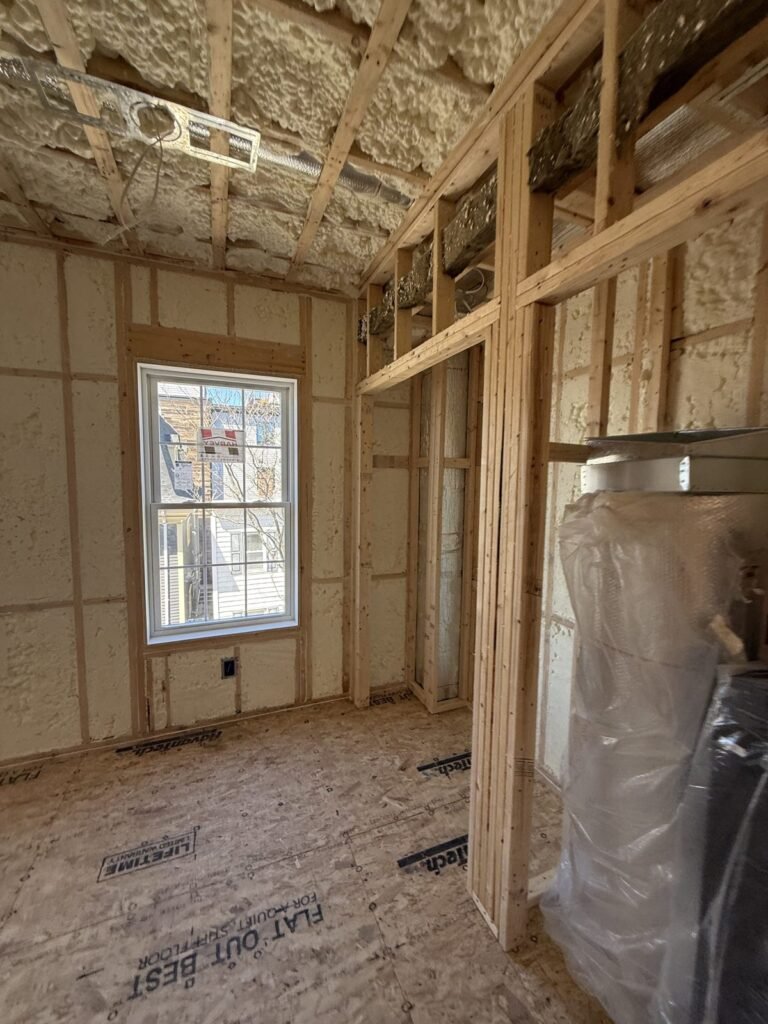Room with foamed walls and ceiling, a framed partition and a wrapped bundle - spray foam insulation in Wareham, MA