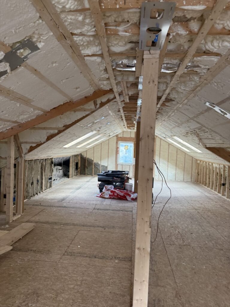 Long attic room with foamed roof slopes and a center support post - HERS rating in Milton, MA