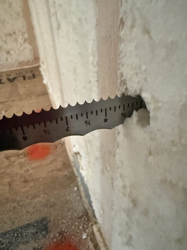 Depth gauge measuring spray foam thickness in a stud bay - HERS rating in Brookline, MA