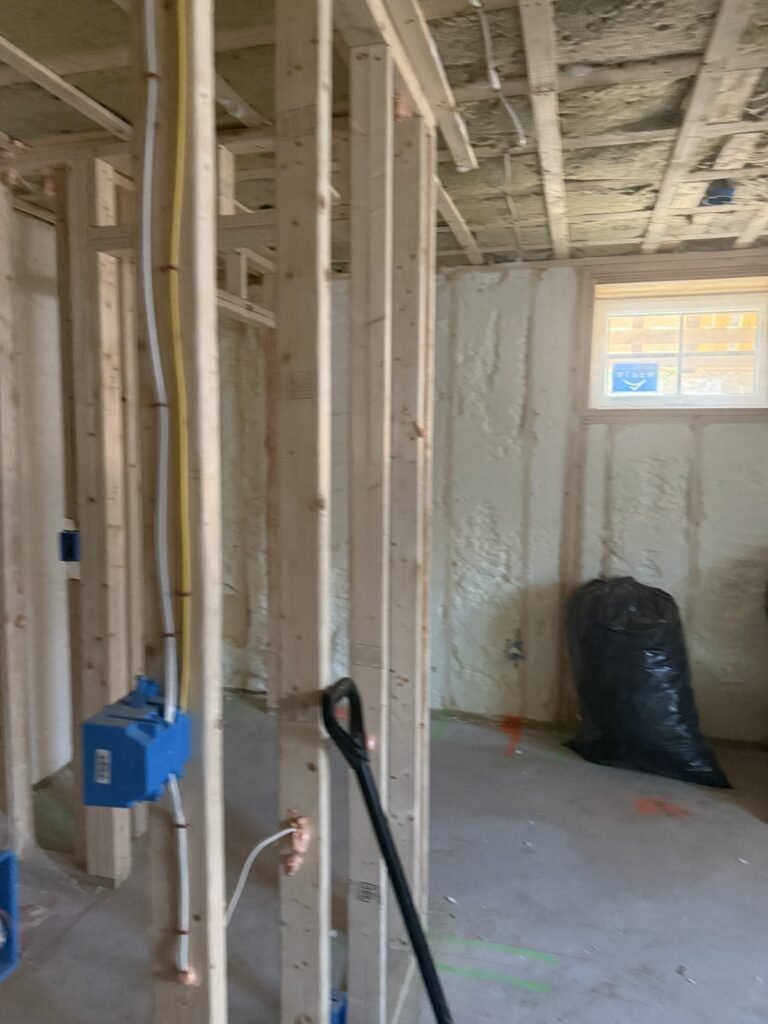 Open stud partition with a blue electrical box in front of foamed exterior walls - HERS rating in Essex, MA