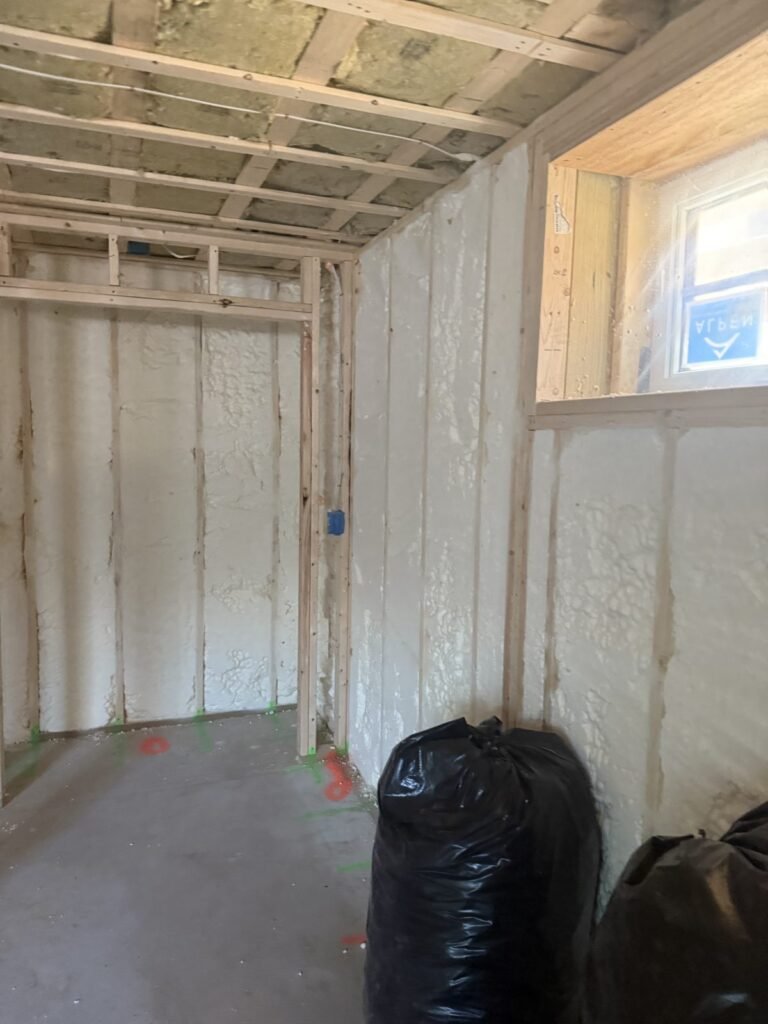 Lower-level room with foamed walls under a framed bulkhead and a small window - spray foam insulation in Warwick, MA