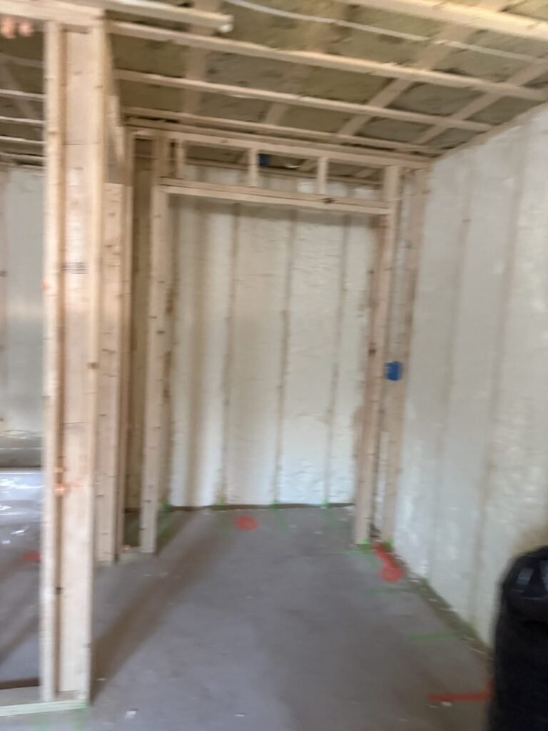Spray-foamed walls behind new partition framing and a doorway opening - HERS rating in Brockton, MA
