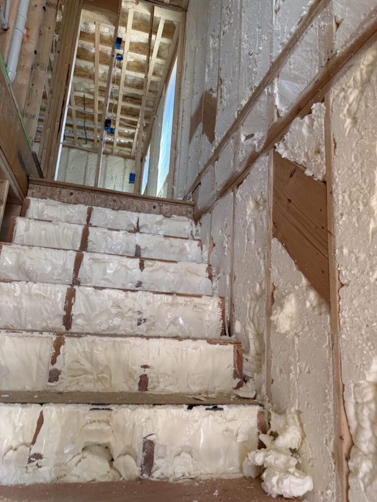 Spray foam sealing the wall alongside a basement stairway - spray foam insulation in Rowe, MA