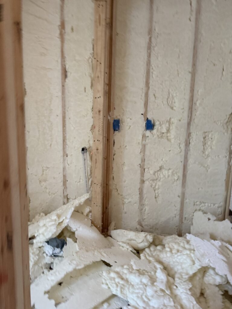 Spray-foamed wall bays with foam trimmings piled at the base - HERS rating in Medfield, MA