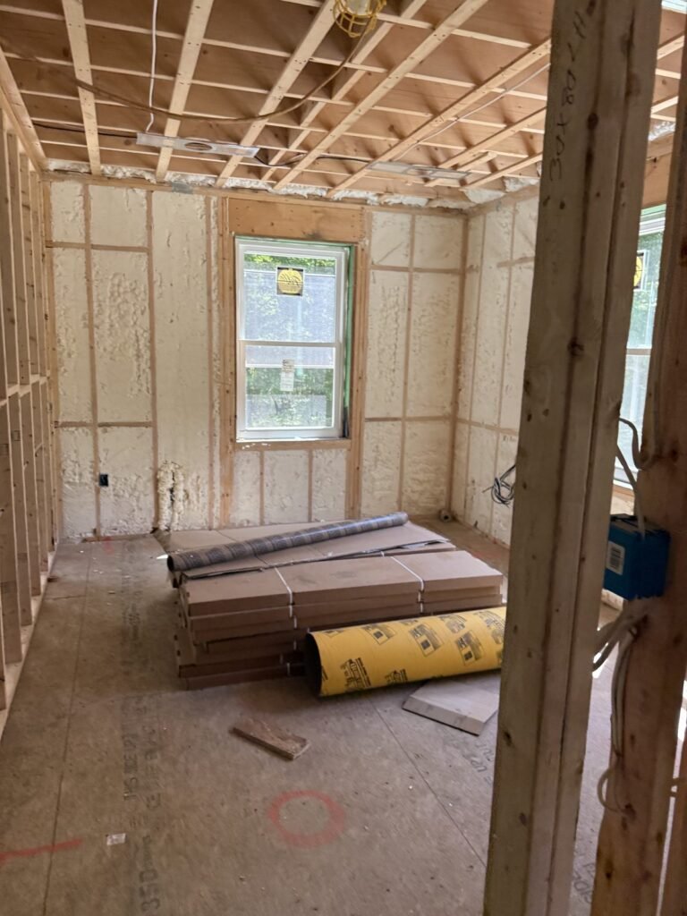 Room with foamed walls and a strapped ceiling, materials stacked on the floor - HERS rating in Fairhaven, MA