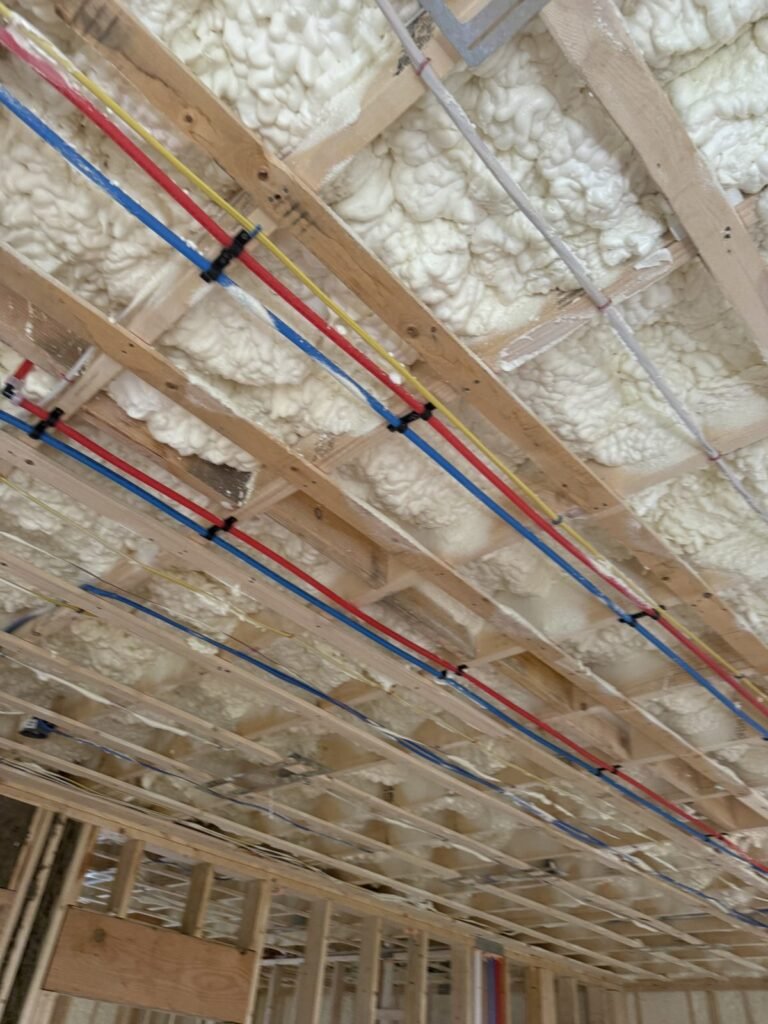 Red and blue PEX lines run through foamed ceiling rafters - HERS rating in Falmouth, MA