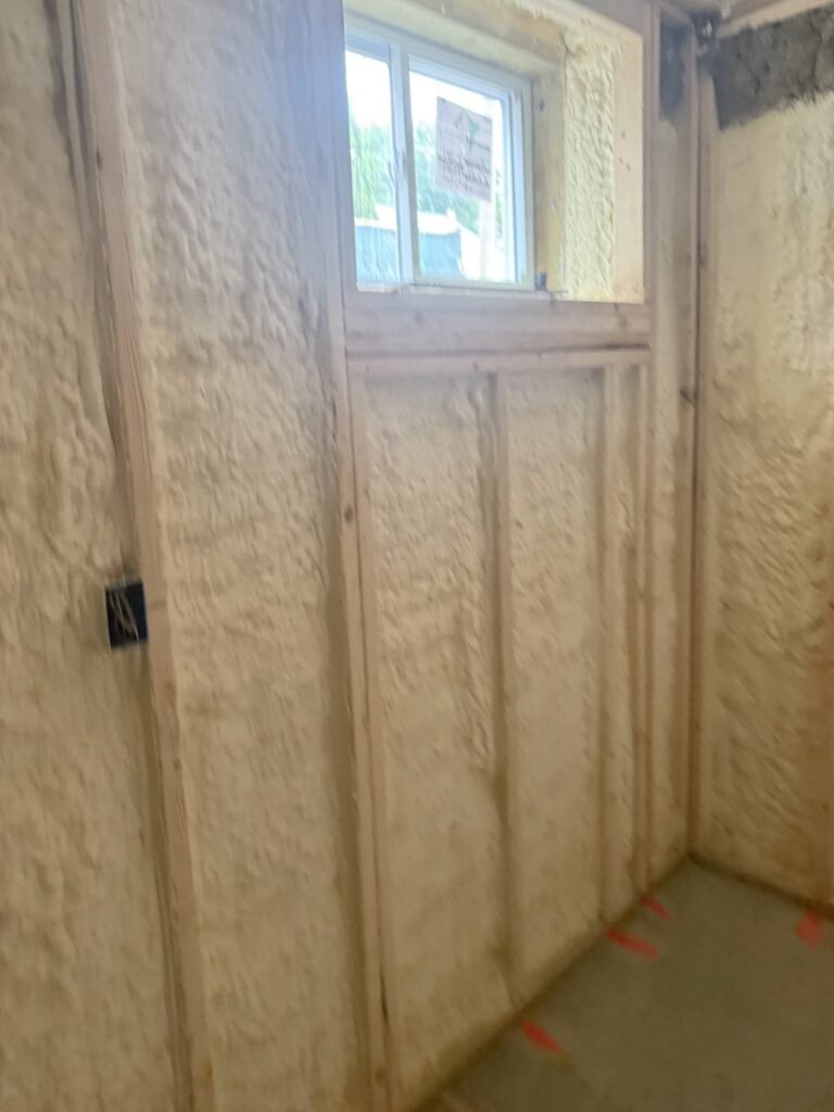 Foamed walls in a small room with a high window and an electrical box - HERS rating in Melrose, MA