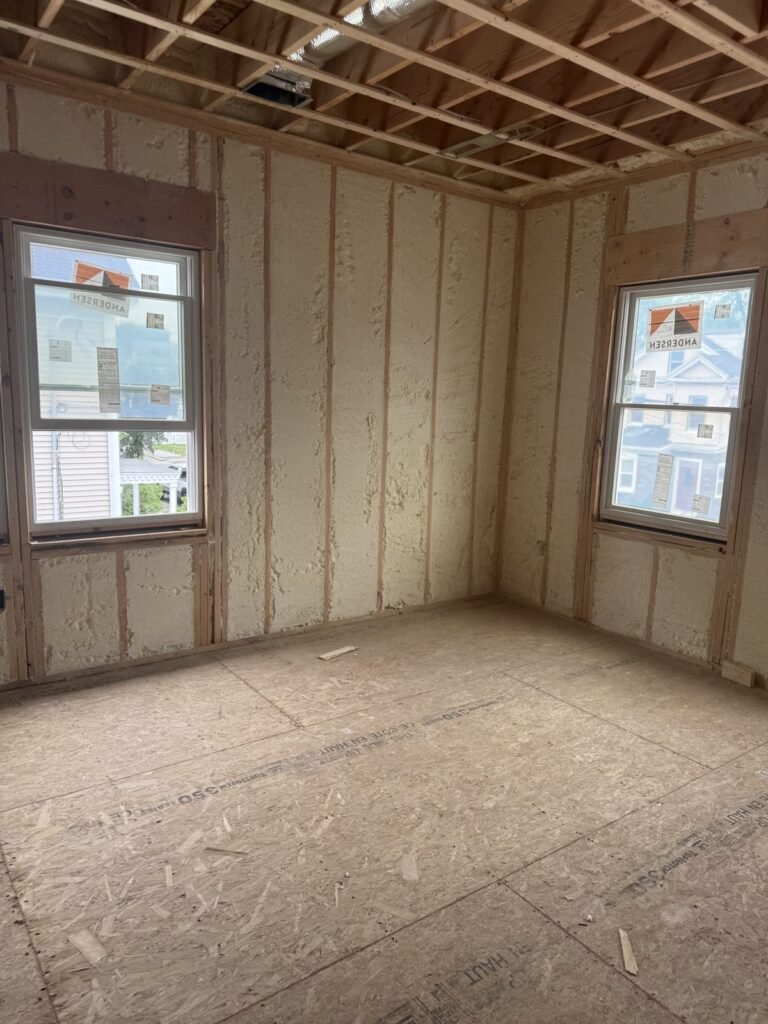 Empty room with spray-foamed walls and two windows - HERS rating in Millis, MA