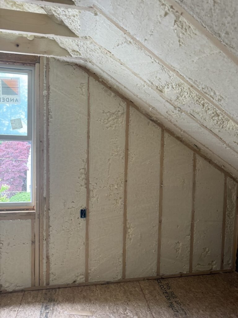 Sloped ceiling and kneewall with cured spray foam next to a window - HERS rating in Clinton, MA