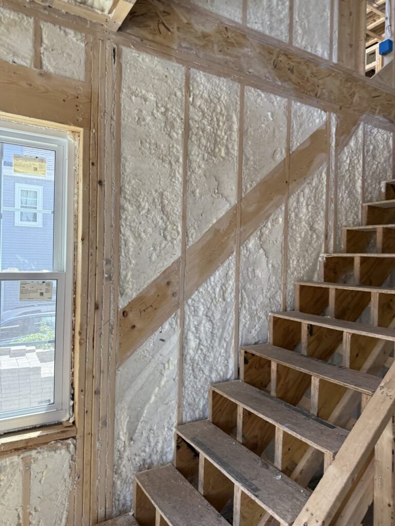 Stair stringers set against a foamed wall beside a window - spray foam insulation in Maynard, MA